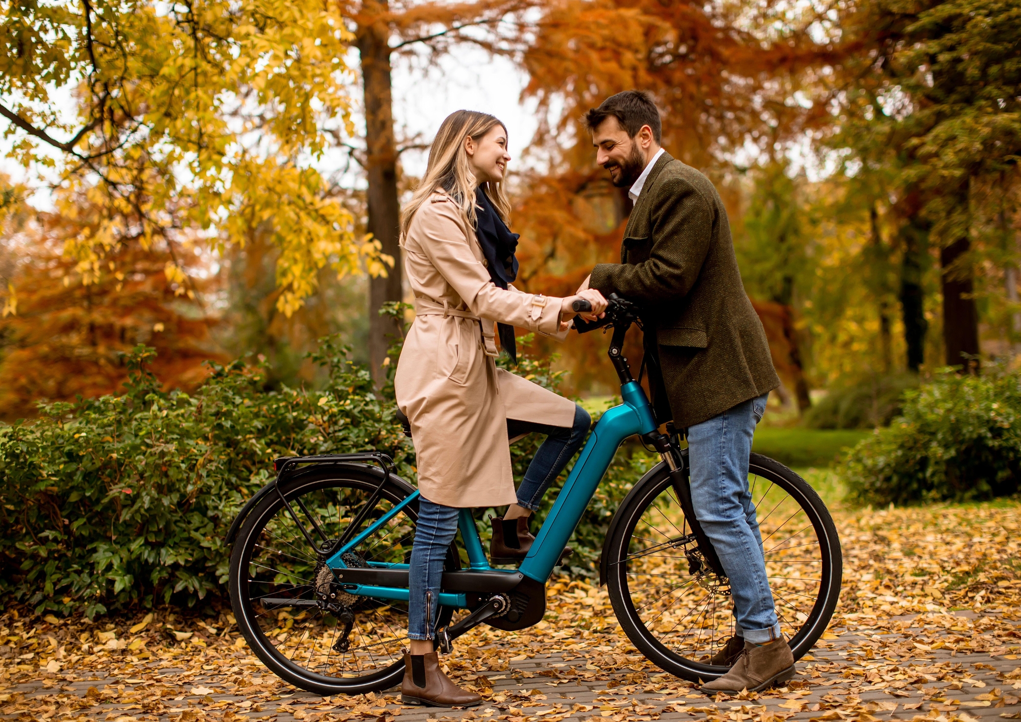 Couple standing together with an electric bike in an autumn park