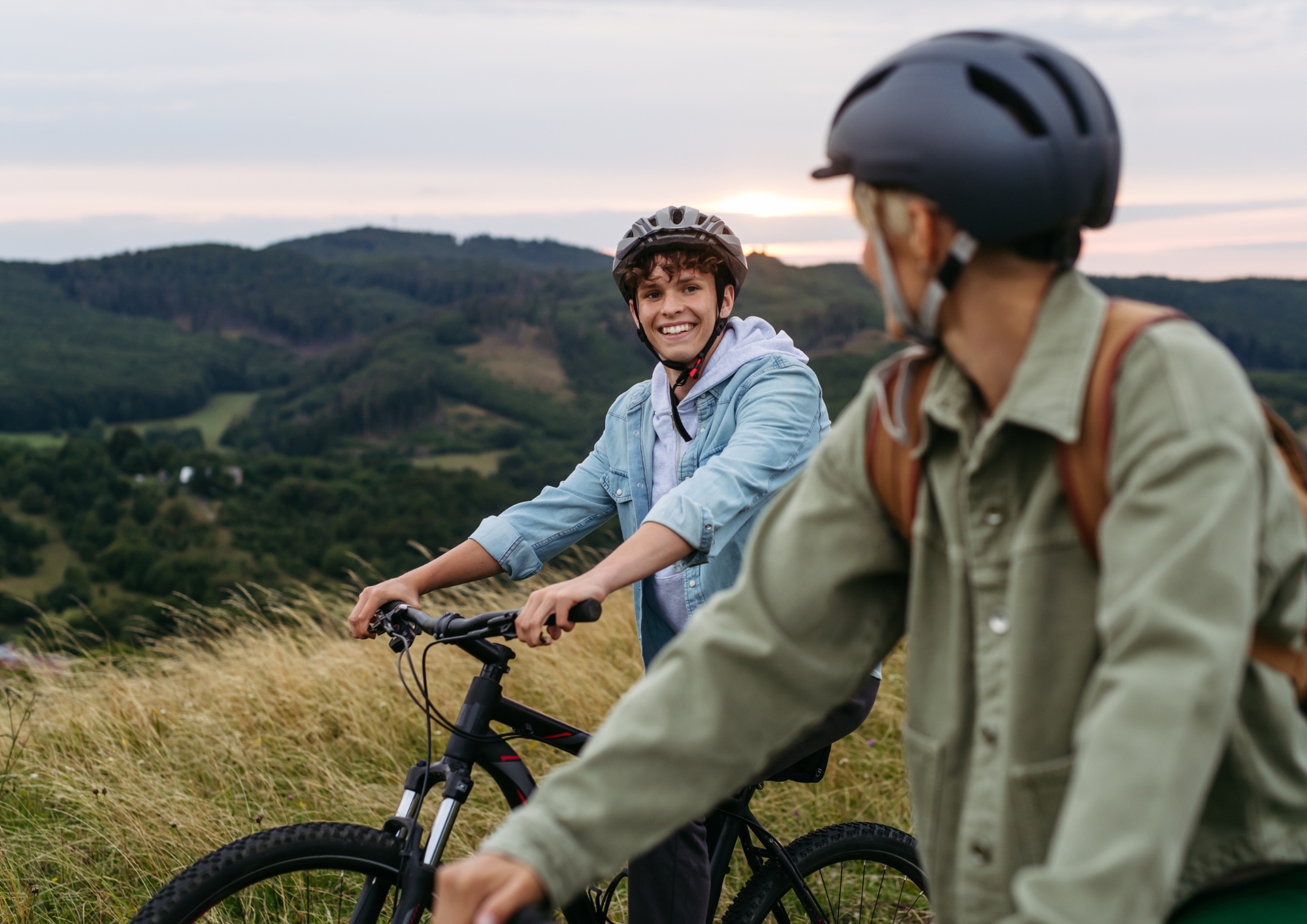 Two cyclists riding through open hillside countryside